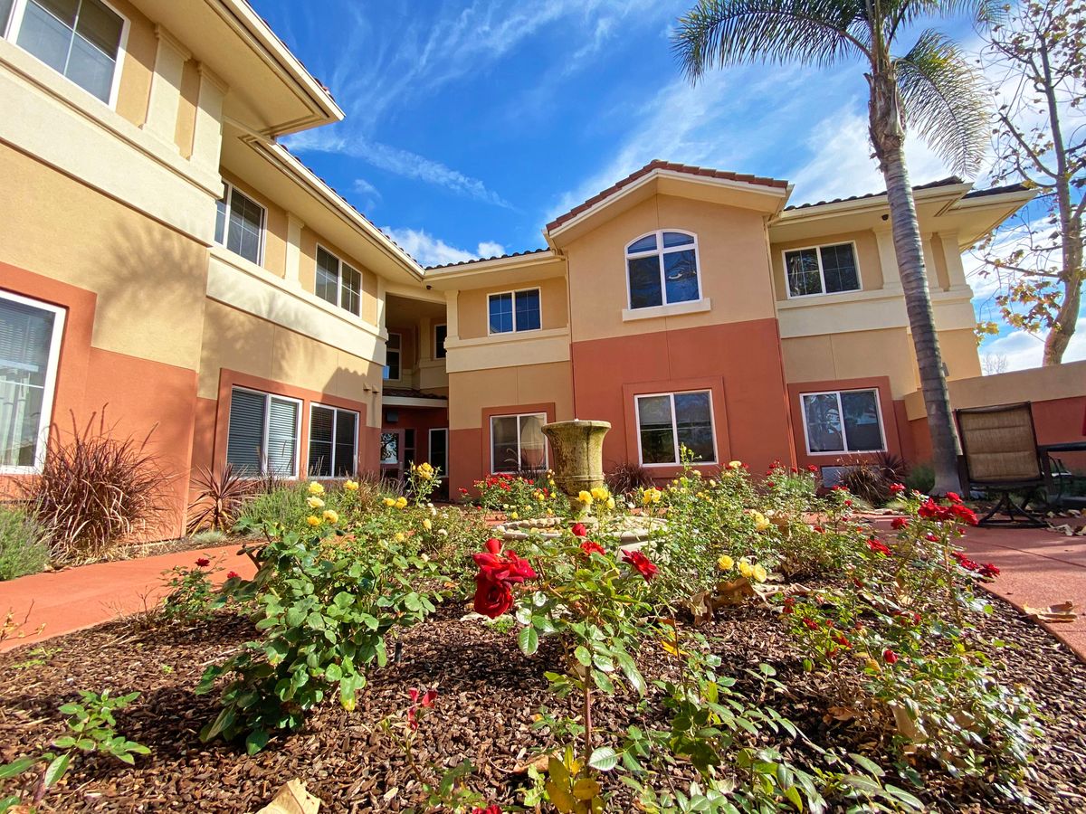 A beautiful residential building surrounded by a vibrant garden of flowers under a clear blue sky.