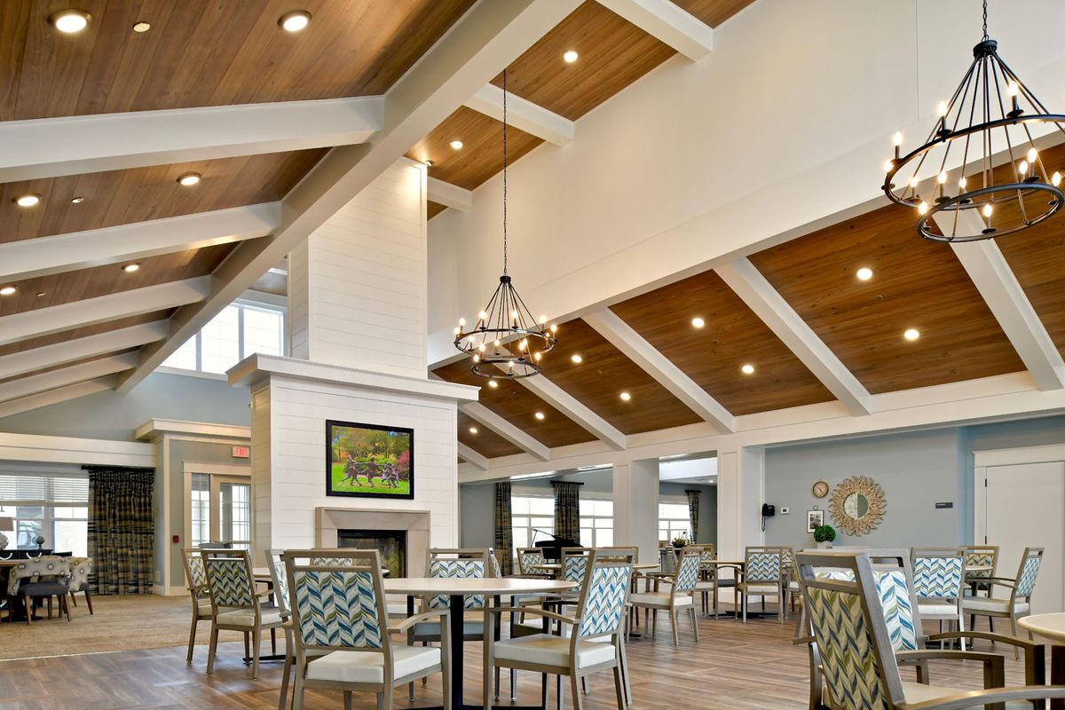 A spacious and modern living area featuring high ceilings with wooden panels, elegant chandeliers, and stylish furniture.