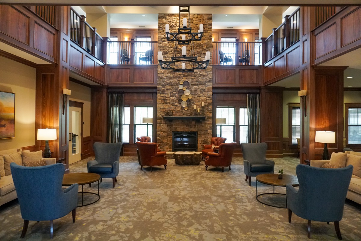 A cozy lobby with a central stone fireplace and comfortable seating.