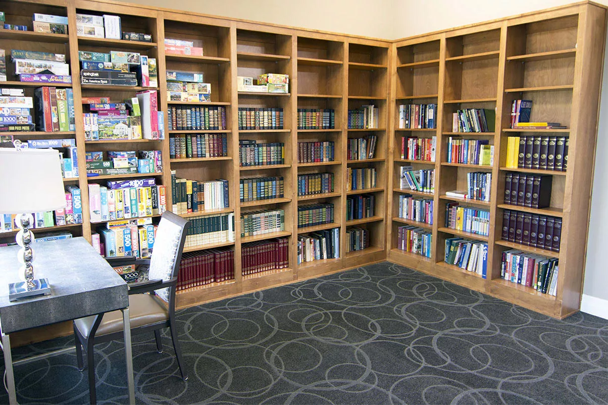 A cozy library corner with wooden bookshelves filled with books and a reading table with chairs.