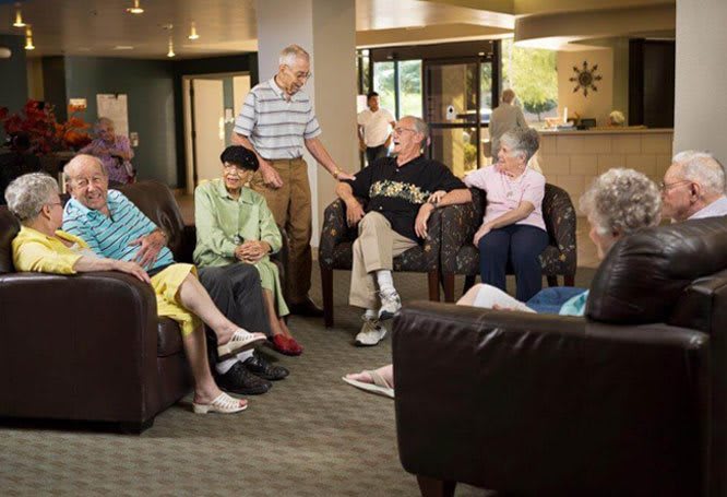 A group of seniors socializing in a community room setting.