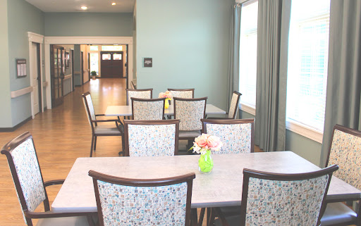 A spacious dining area featuring a light blue wall, modern furniture, and a decorative floral centerpiece.