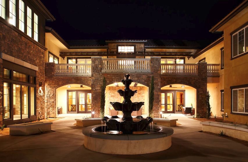 A beautifully illuminated building at night with a fountain in the courtyard.