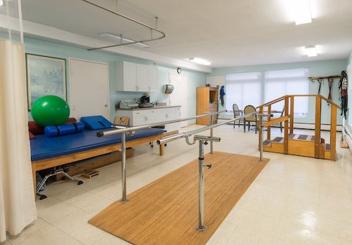 A well-equipped physical therapy room with parallel bars and other rehabilitation equipment.