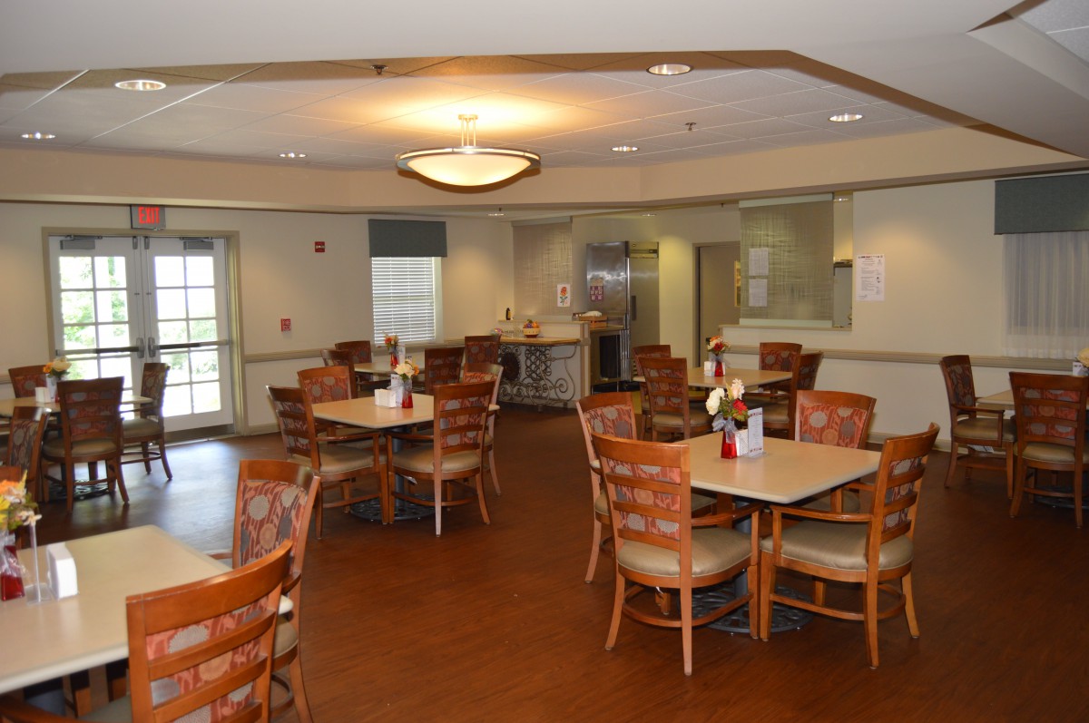 An empty dining area with neatly arranged tables and chairs, featuring warm lighting.