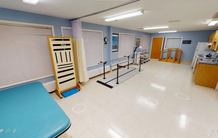 A well-lit rehabilitation room equipped with parallel bars and exercise apparatus for physical therapy sessions.