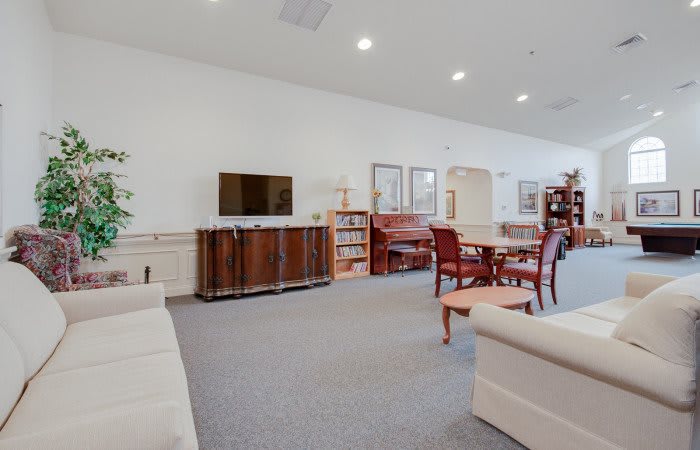 A spacious living room featuring a television, piano, and comfortable seating area.