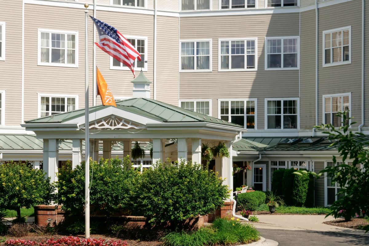 A residential building with an entrance, featuring greenery and flags.