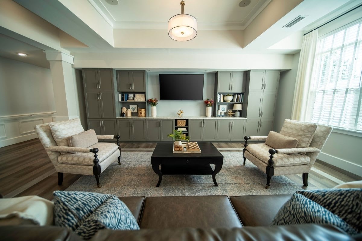 A modern living room featuring comfortable armchairs, a large TV, and a stylish coffee table.