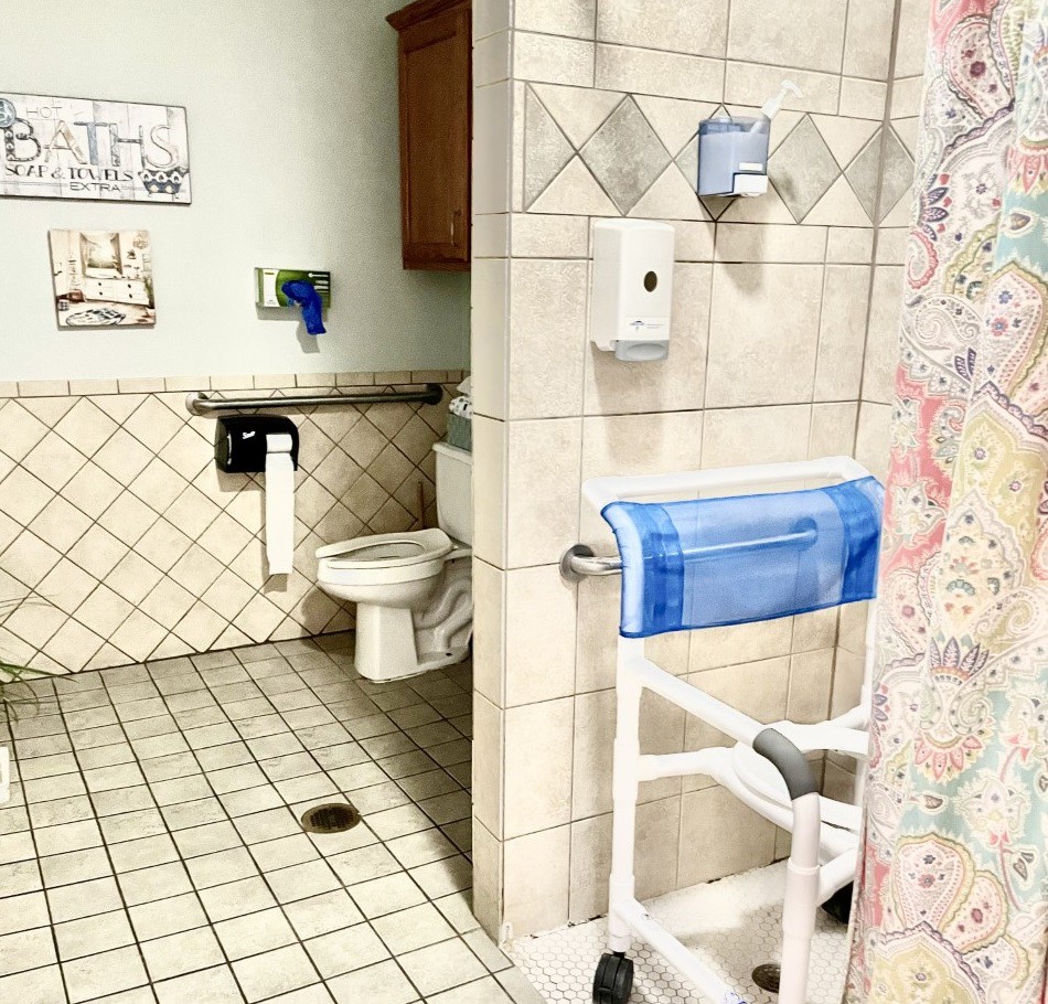 An accessible bathroom with handrails and a wheelchair-accessible shower.