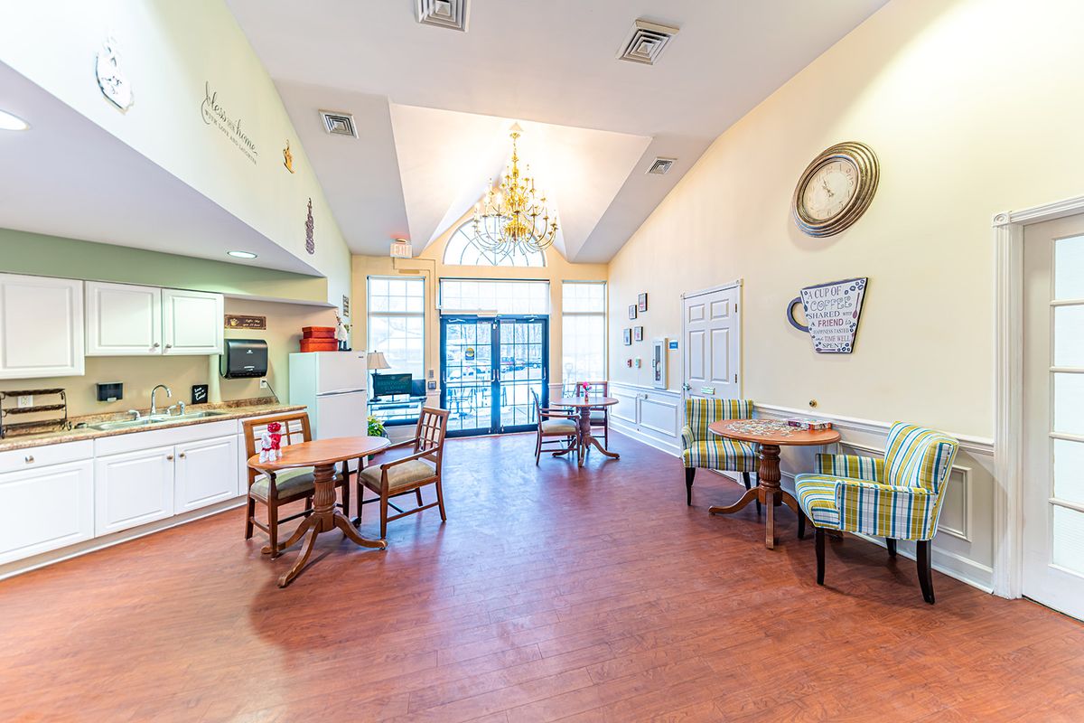A cozy kitchen and dining area with a chandelier, tables, and chairs.