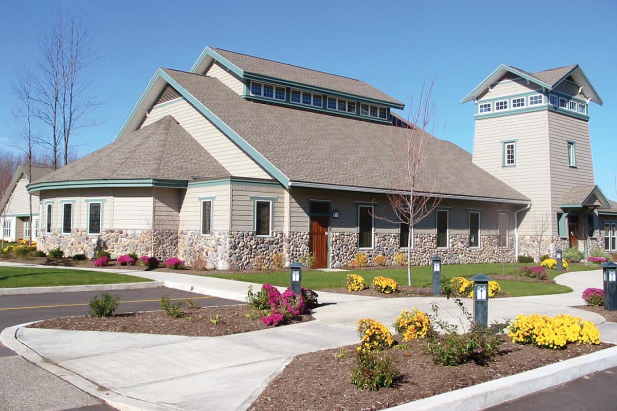 A suburban residential house with well-maintained landscaping and a clear blue sky.