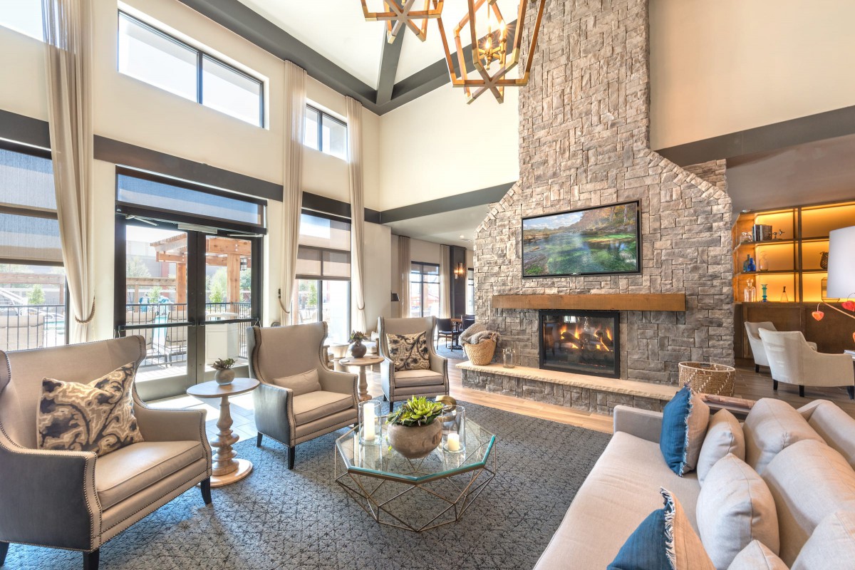 A luxurious living room with a high ceiling, stone fireplace, and modern decor.