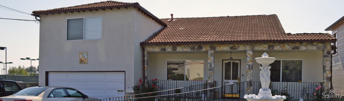 A house with a tiled roof, stone accents, and a small patio area.