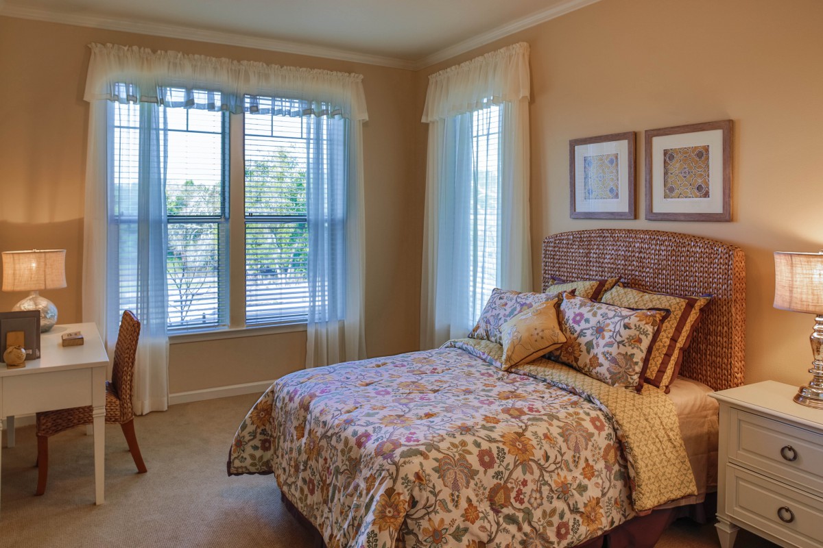 A cozy bedroom with a large window, featuring elegant decor and comfortable furnishings.
