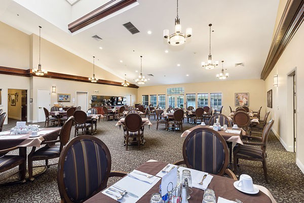 A spacious restaurant dining area with elegantly set tables and chandeliers.