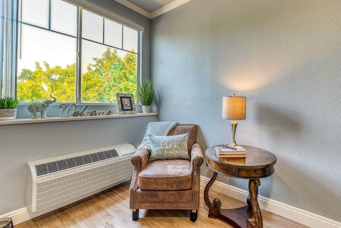 A cozy reading nook featuring a comfortable armchair, side table with a lamp, and a window view.