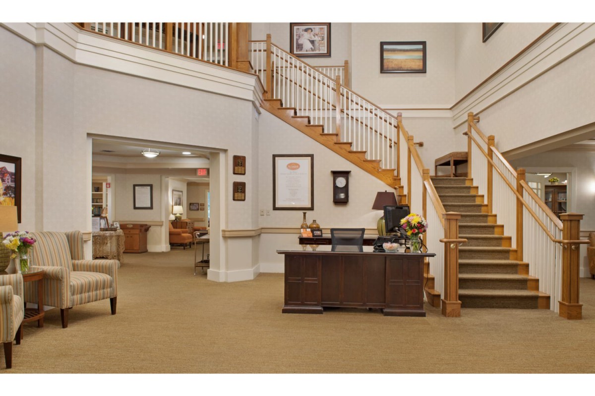 A spacious lobby with a central reception desk and a grand staircase.