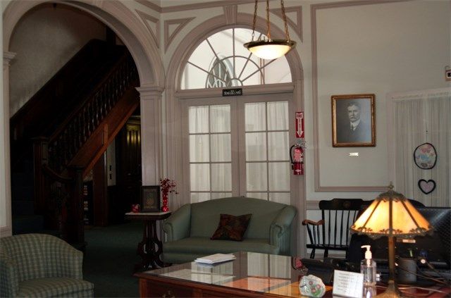 A cozy lobby area with traditional furniture and a portrait on the wall.