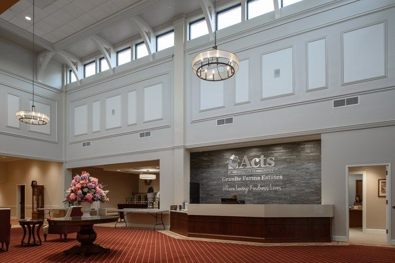 A modern hotel lobby with a reception desk, chandelier, and floral arrangement.