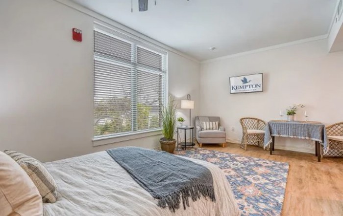 A modern and cozy bedroom featuring stylish furniture, a large window with natural light, and tasteful decor.