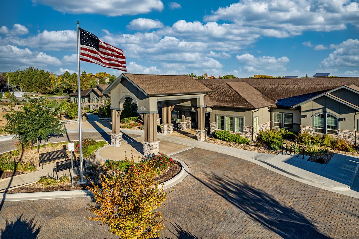 A scenic view of a building entrance with an American flag on a sunny day.