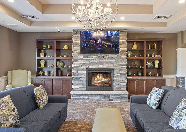 A cozy living room with a stone fireplace, surrounded by shelves and comfortable seating.