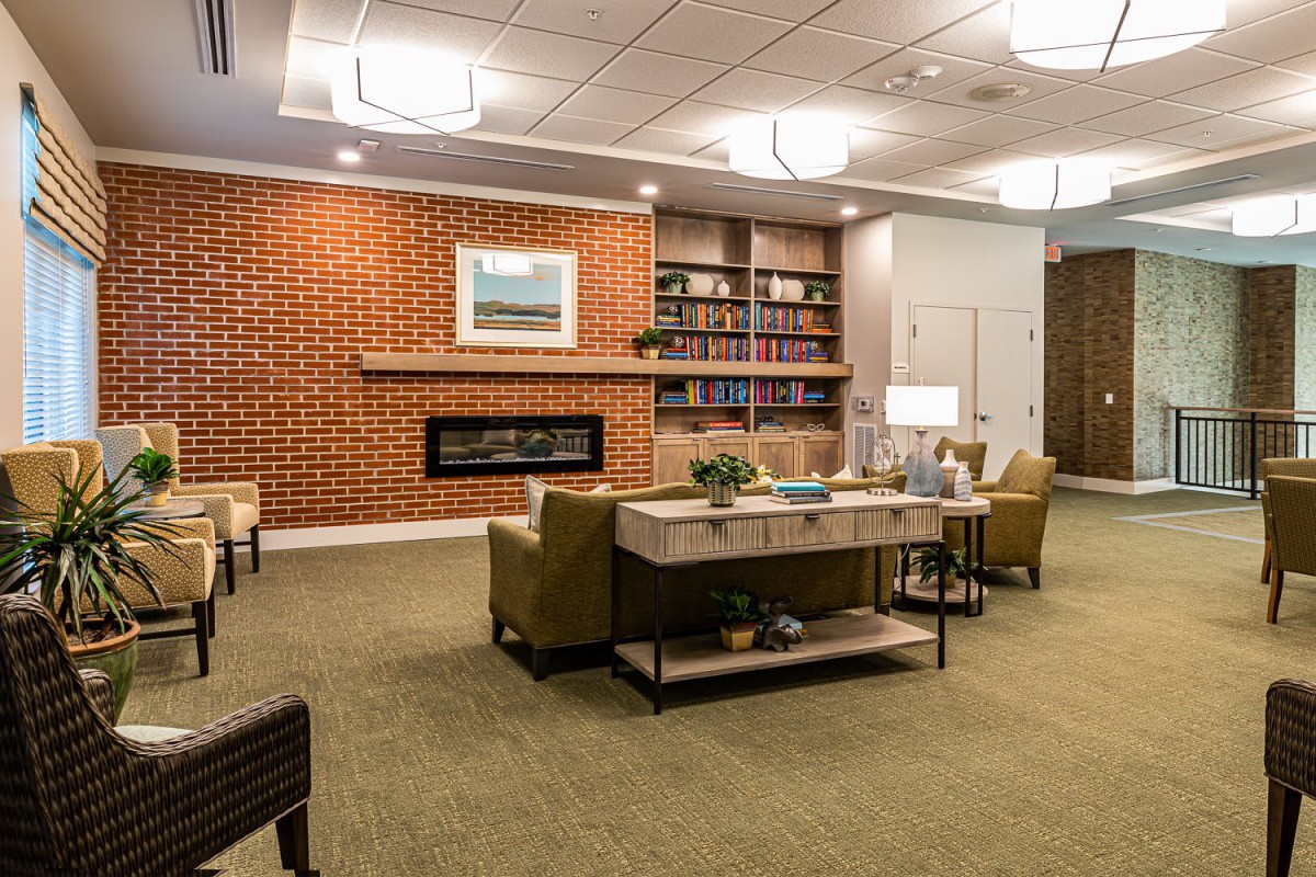 A modern and cozy living room featuring a fireplace, comfortable seating, and a bookshelf.