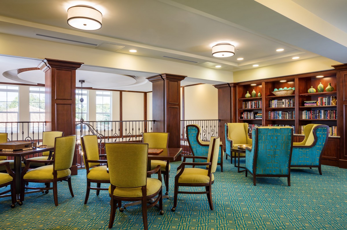 A cozy library seating area with chairs, tables, and bookshelves.