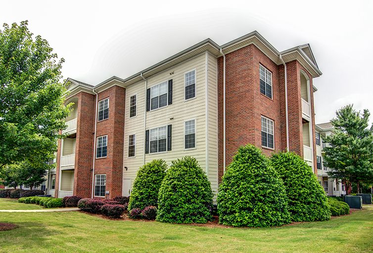 A modern apartment building with a brick exterior and well-maintained landscaping.