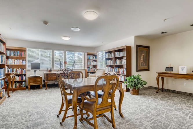 A spacious and well-lit dining area with wooden furniture and bookshelves.