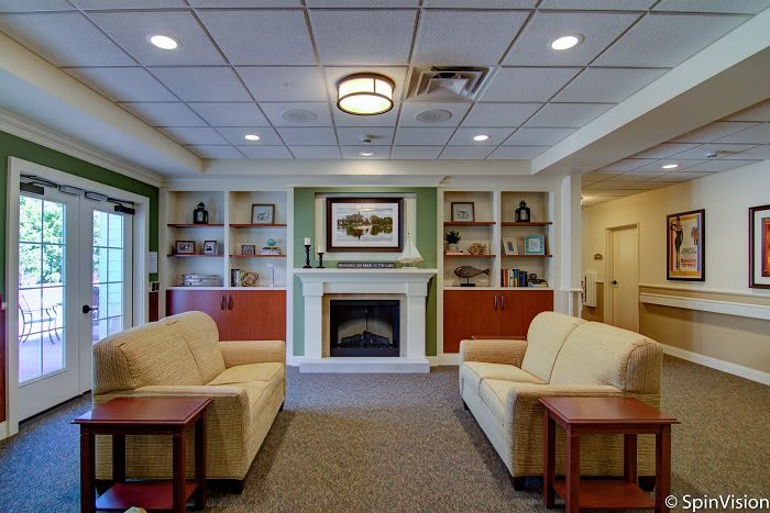 A cozy living room with couches facing a fireplace, surrounded by built-in shelves and decorative elements.