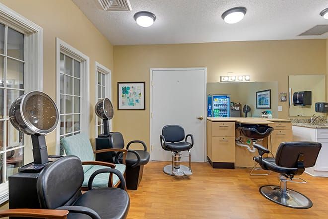 Interior view of a salon with chairs, hair dryers, and a mirror.