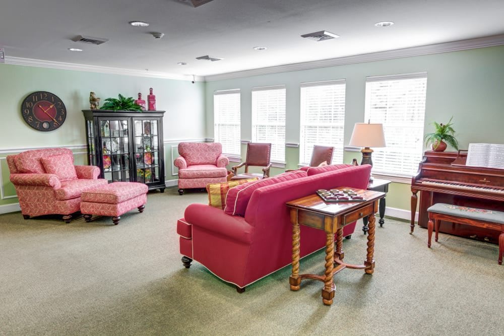 A cozy living room with pink sofas and chairs, illuminated by natural light from large windows.