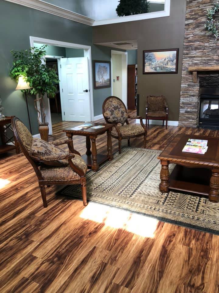 A cozy living room with wood flooring, comfortable furniture, and a stone fireplace.