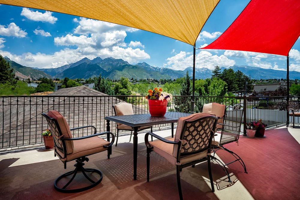 A scenic patio with comfortable seating and vibrant shade sails overlooking a mountain landscape.