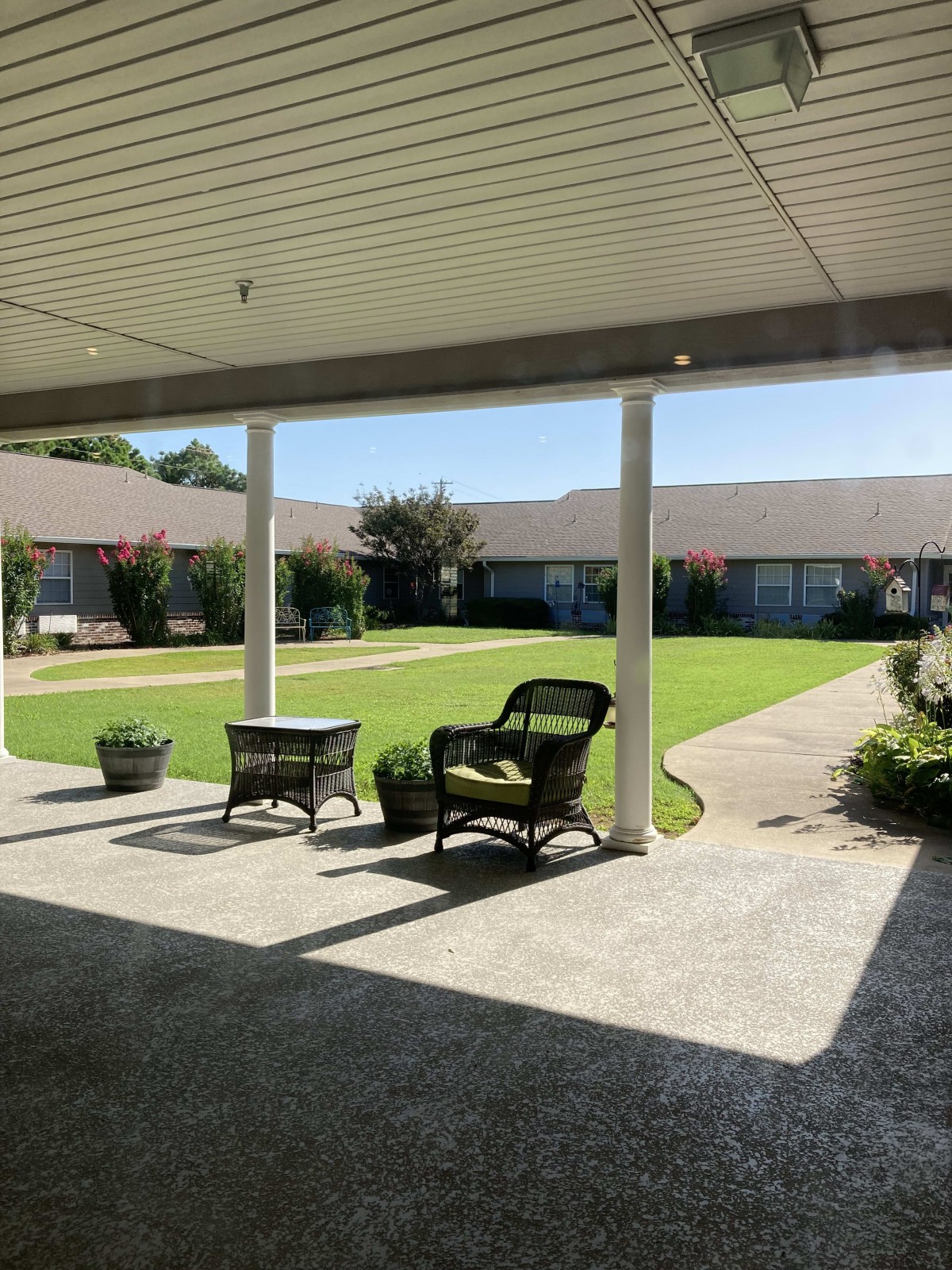 A peaceful courtyard with chairs and a lush green garden.