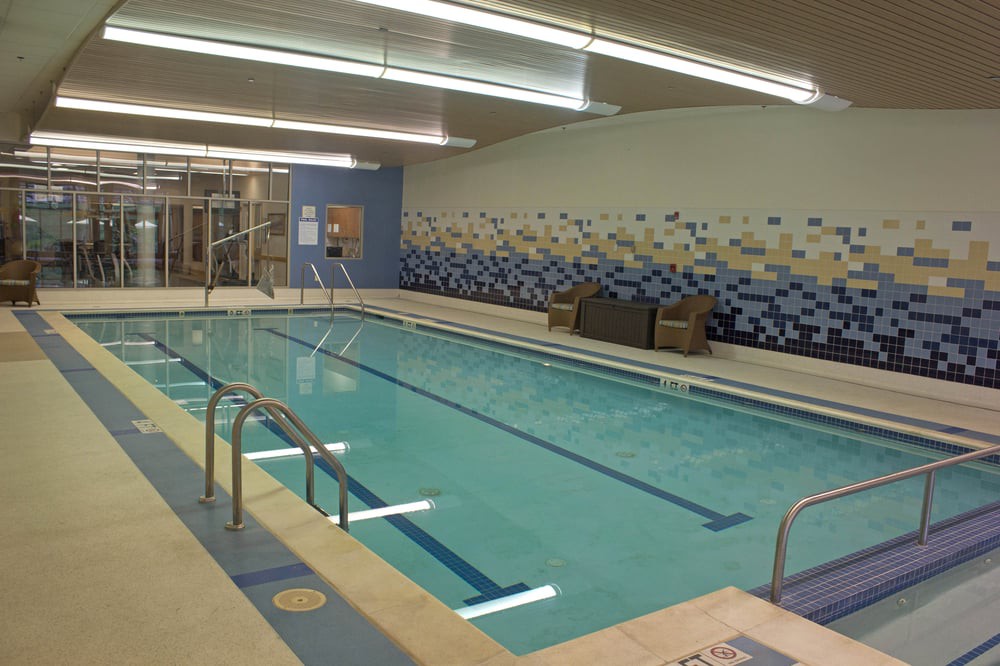 A modern indoor swimming pool with lounge chairs and a stylish tile design.