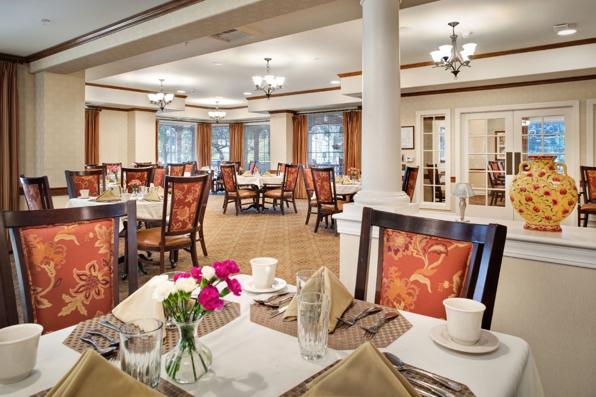 An elegant dining room with neatly arranged tables and chairs, adorned with flowers.