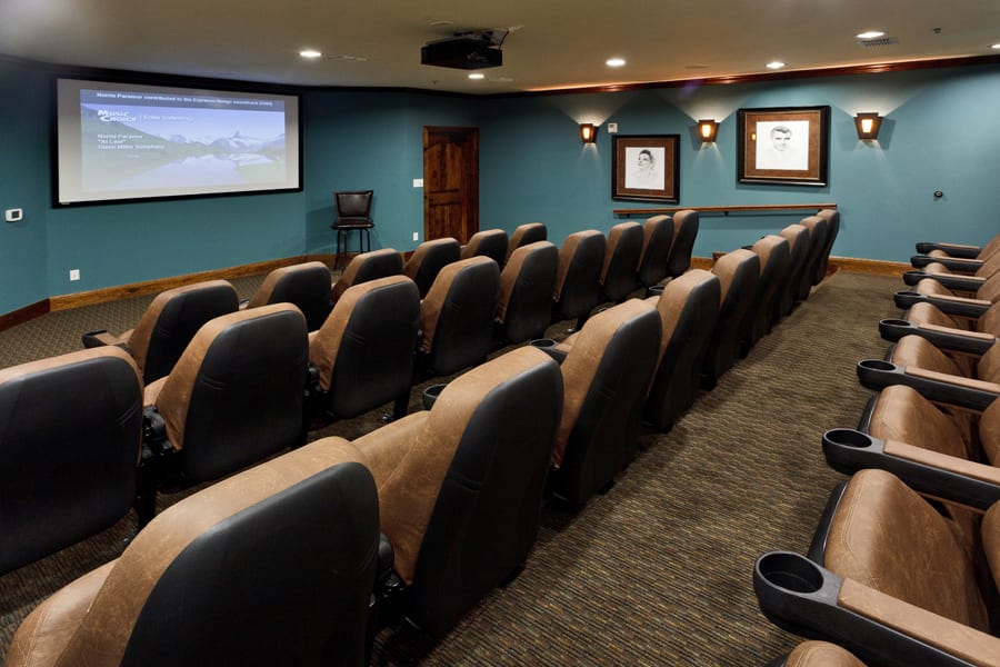 A cozy home theater setup with multiple rows of comfortable seating and a large screen.