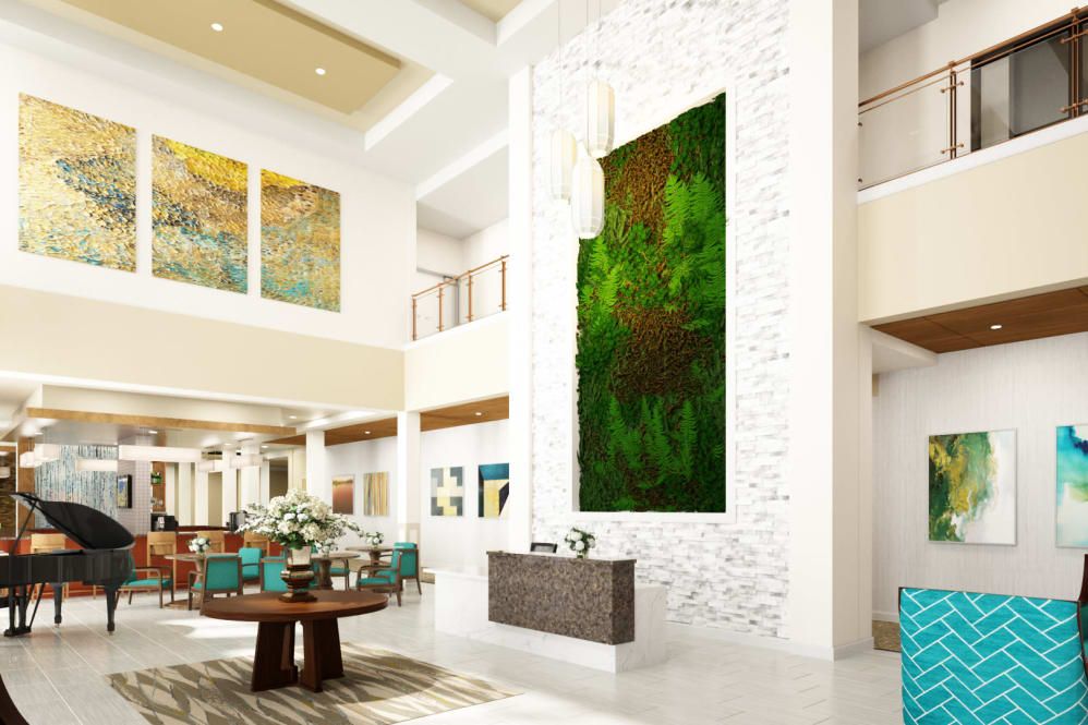 A spacious, modern lobby featuring a striking green wall art piece and elegant decor.