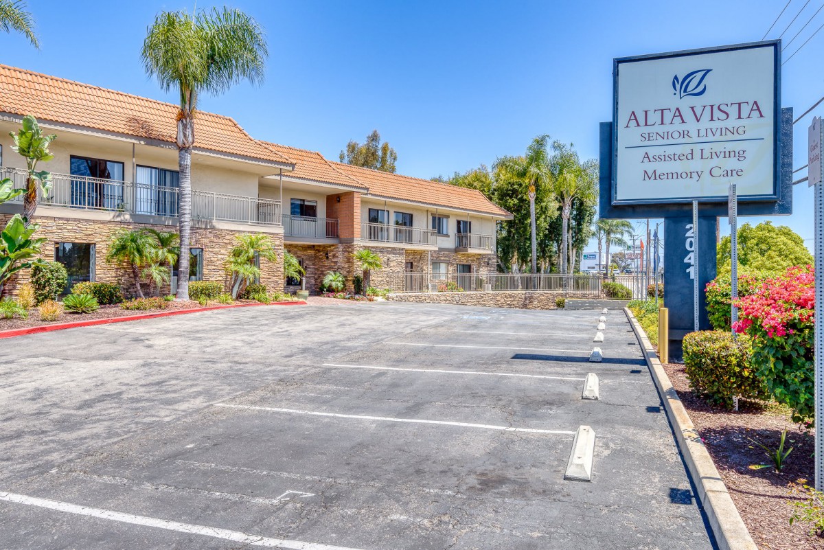 A view of a motel with an empty parking lot under a clear blue sky.