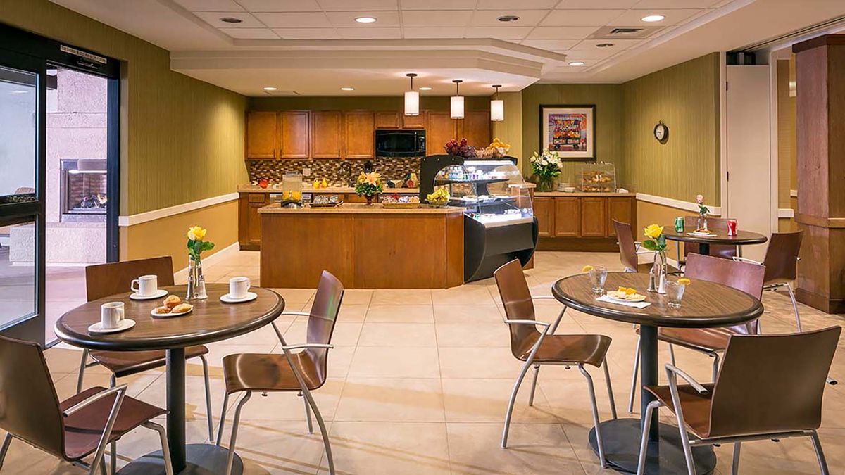 A modern cafe interior with tables, chairs, and a serving counter.
