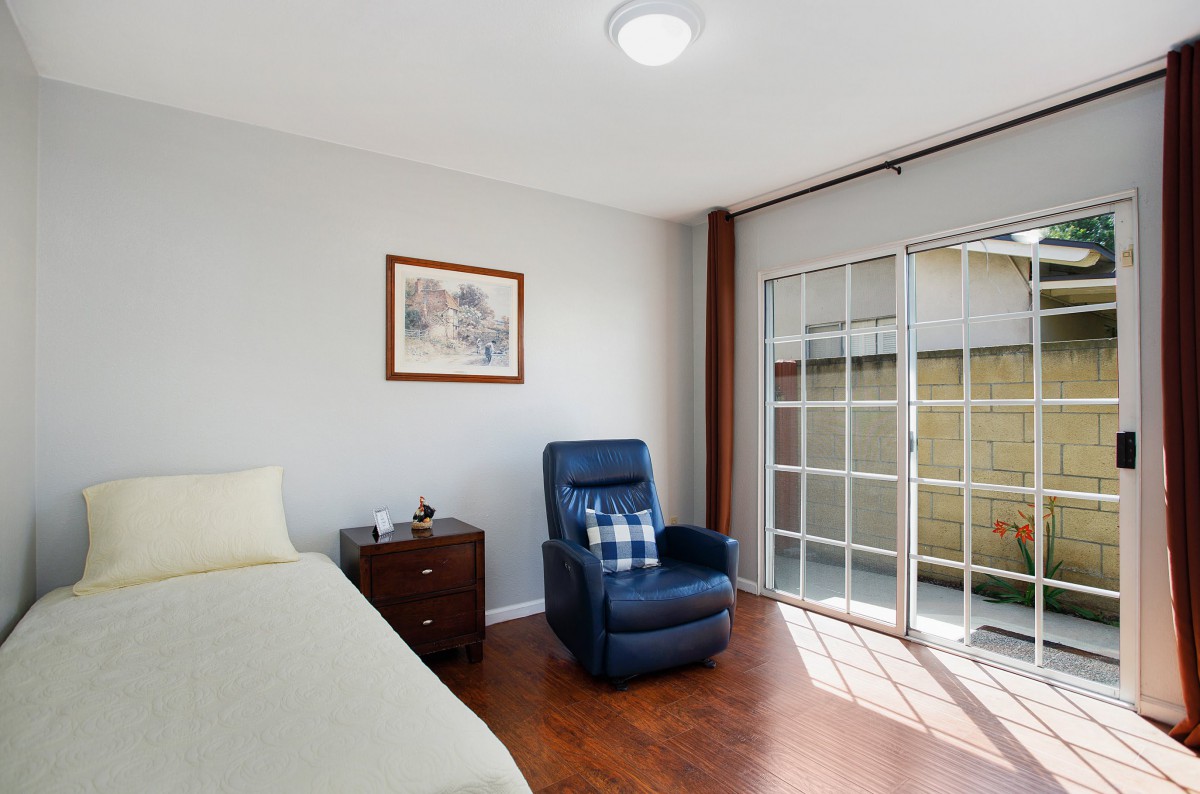 A minimalist bedroom with a recliner and sliding glass doors.