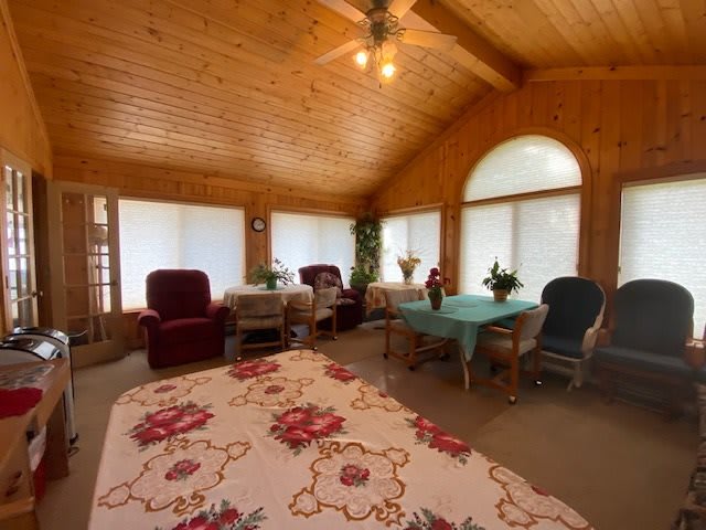 A cozy sunroom with wooden interiors, featuring comfortable seating arrangements and ample natural light.