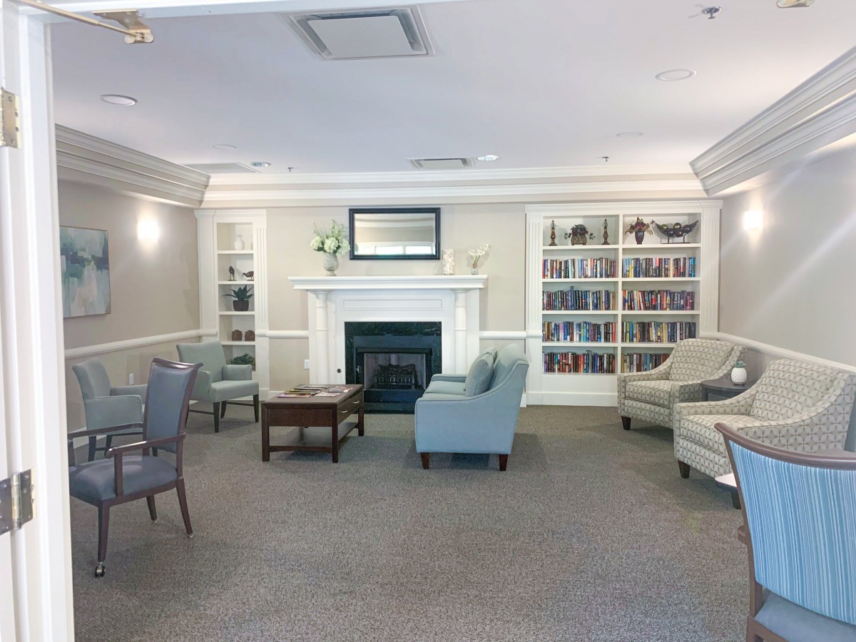 A cozy living room with a fireplace, surrounded by bookshelves and comfortable seating.