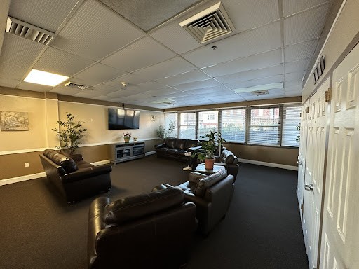 A cozy lounge area featuring comfortable sofas, indoor plants, and a TV.