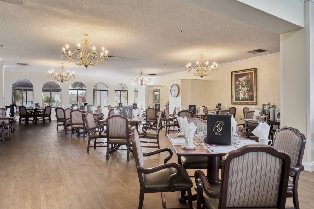 An elegant dining room with chandeliers and neatly arranged tables and chairs.