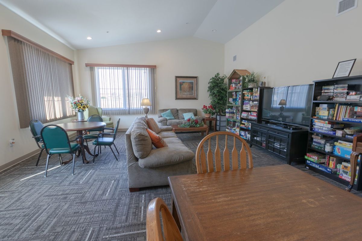 A spacious living room with a dining area, featuring a couch, television, and bookshelves.