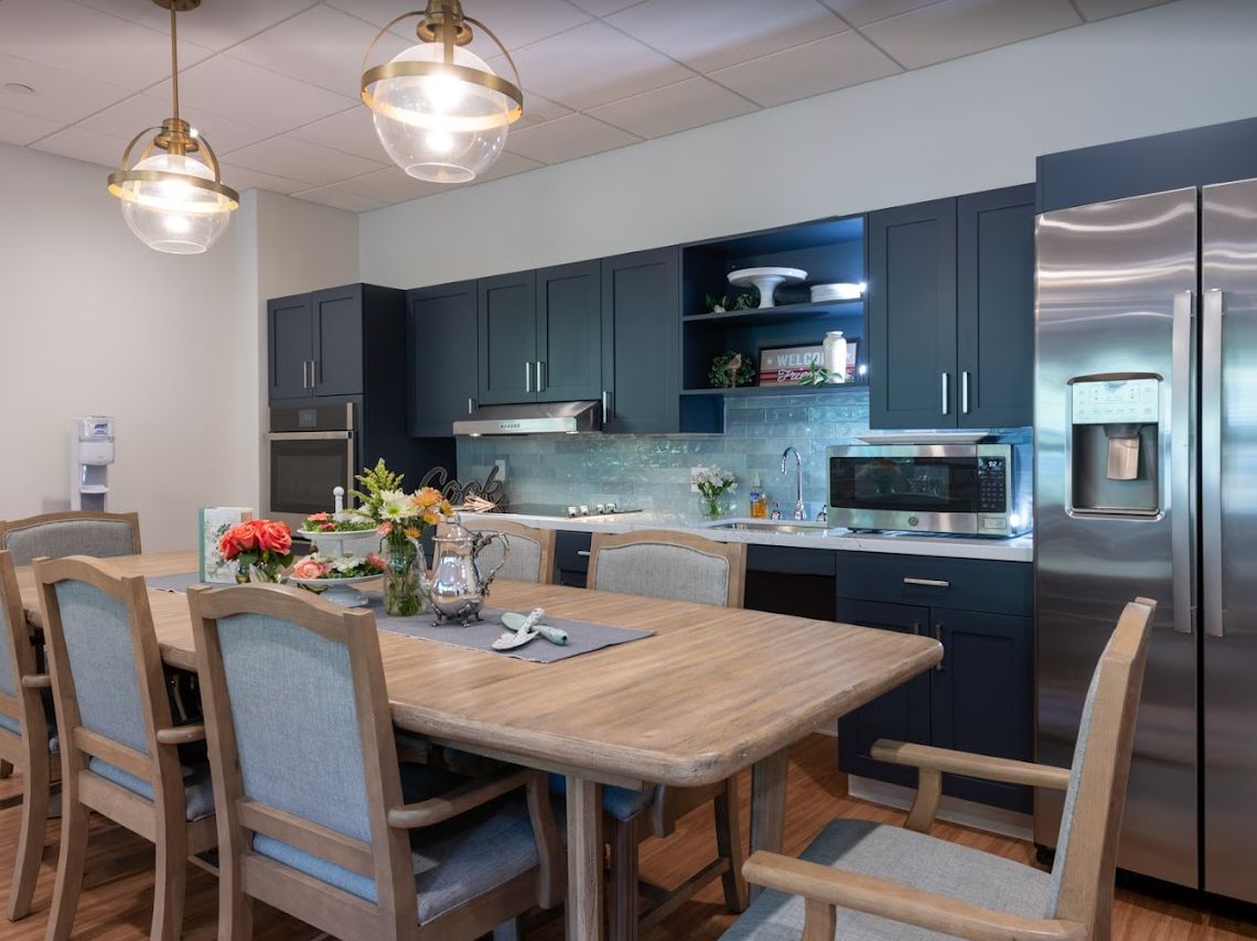 A modern kitchen and dining area featuring a wooden table with chairs, stylish pendant lighting, and sleek cabinetry.